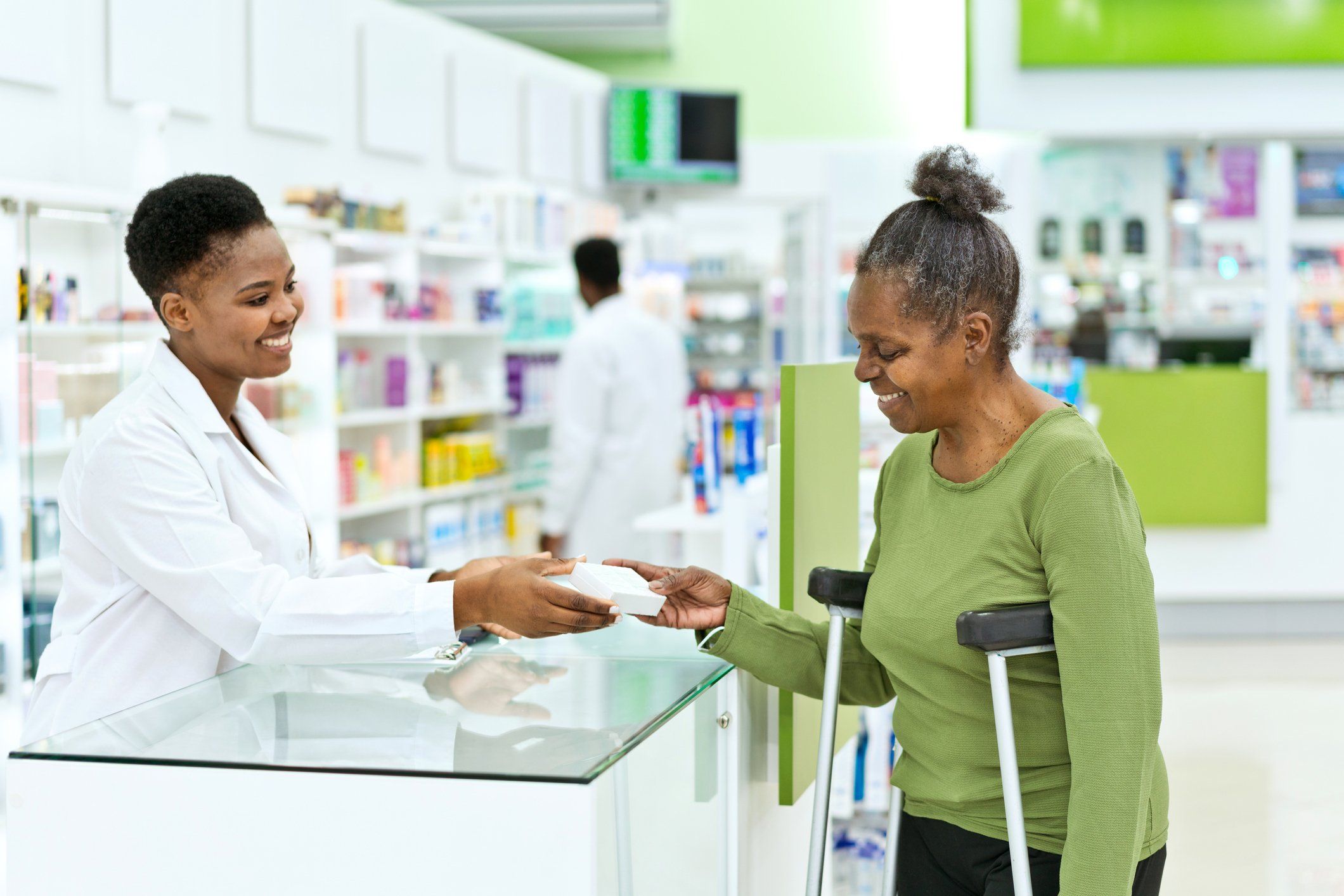 Pharmacist aids woman at counter.